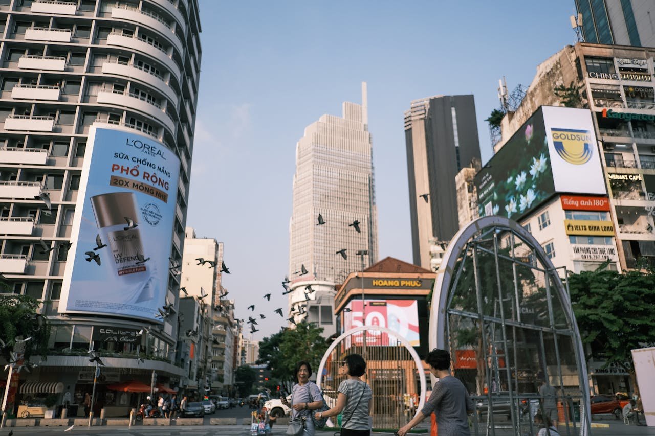 Vibrant urban street view featuring people, skyscrapers, and advertisements in Ho Chi Minh City.