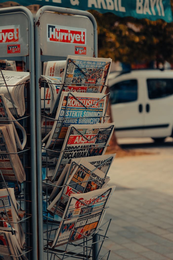 Vertical shot of a newspaper stand with various magazines on a city sidewalk.