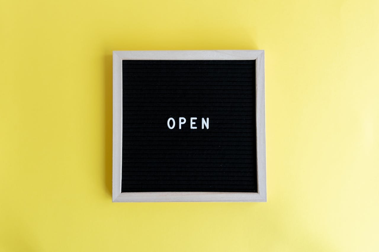 Minimalist blackboard frame displaying the word 'OPEN' on a vibrant yellow background.